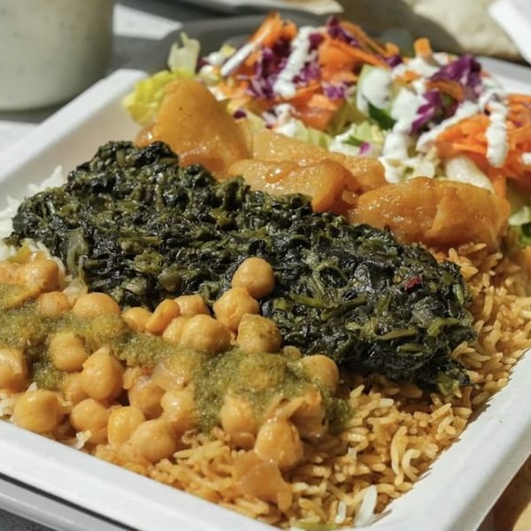 A Grill Kabob plate with rice, chickpeas, spinach, potatoes, and a side salad with dressing.