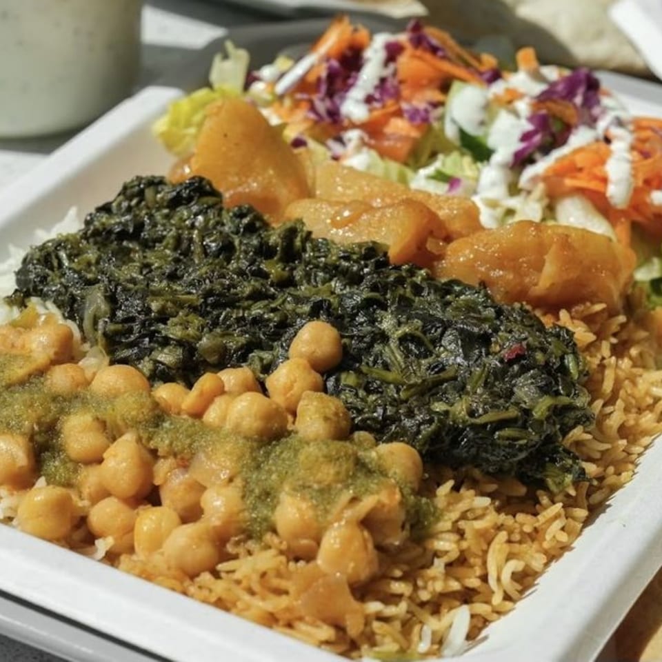 A Grill Kabob plate with rice, chickpeas, spinach, potatoes, and a side salad with dressing.
