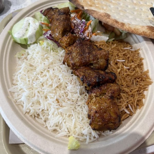 Grill Kabob plate with chicken kebab, white rice, brown rice, salad, and flatbread.