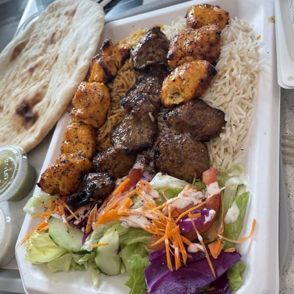 A Grill Kabob platter with chicken and beef kebabs, rice, salad, and naan bread.